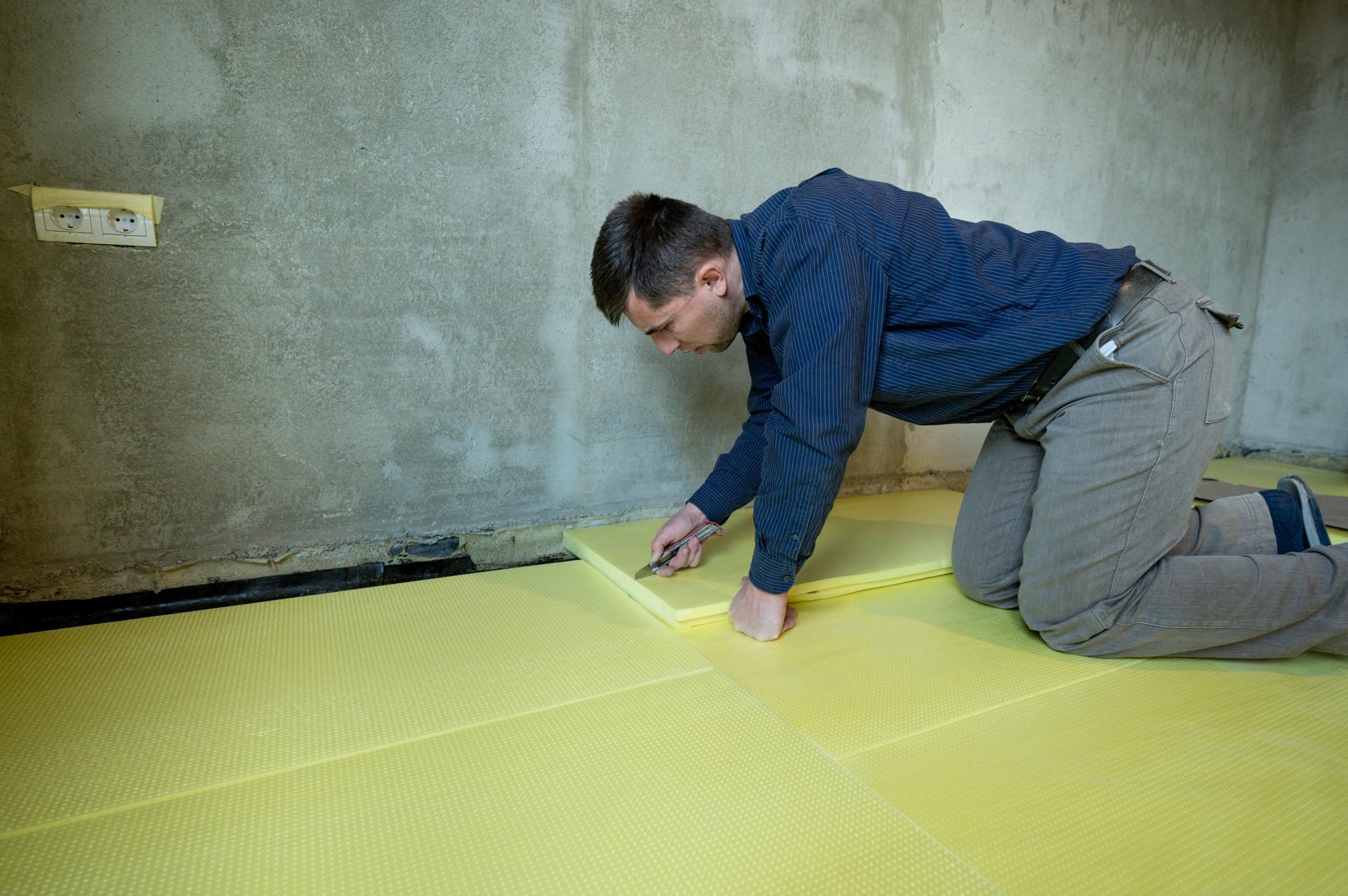 Close-up of the master cuts the size of expanded polystyrene on the floor, the process of floor insulation in the house.