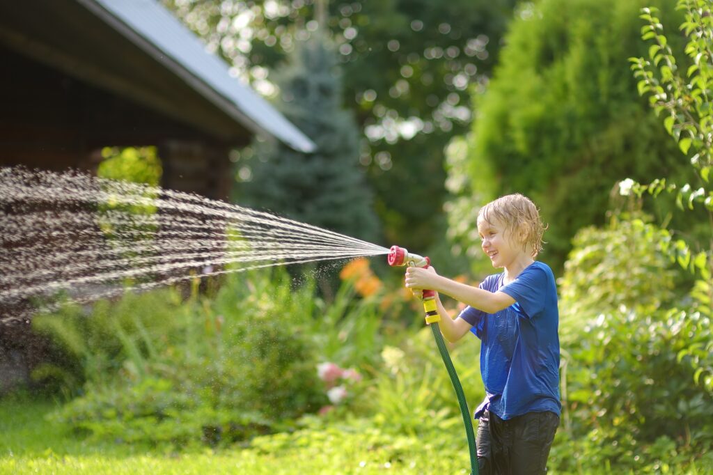 Summer Plumbing Prep: Essential Maintenance for Myrtle Beach Homes 1 Funny little boy playing with garden hose in sunny backyard.